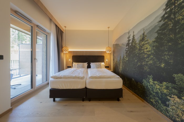 [Translate to english:] Waldwipfel Juniorsuite - Doppelbett neben Balkon