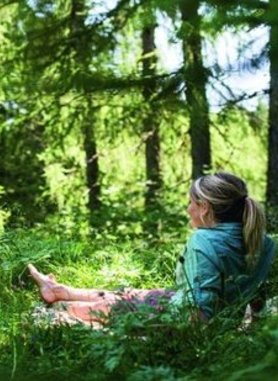 Dame auf dem Waldboden sitzend inmitten des Waldes