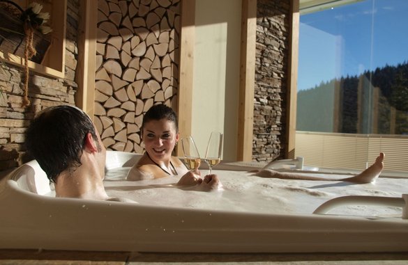 Un couple avec du champagne dans la baignoire à remous de l'hôtel de bien-être de la Forêt-Noire. 